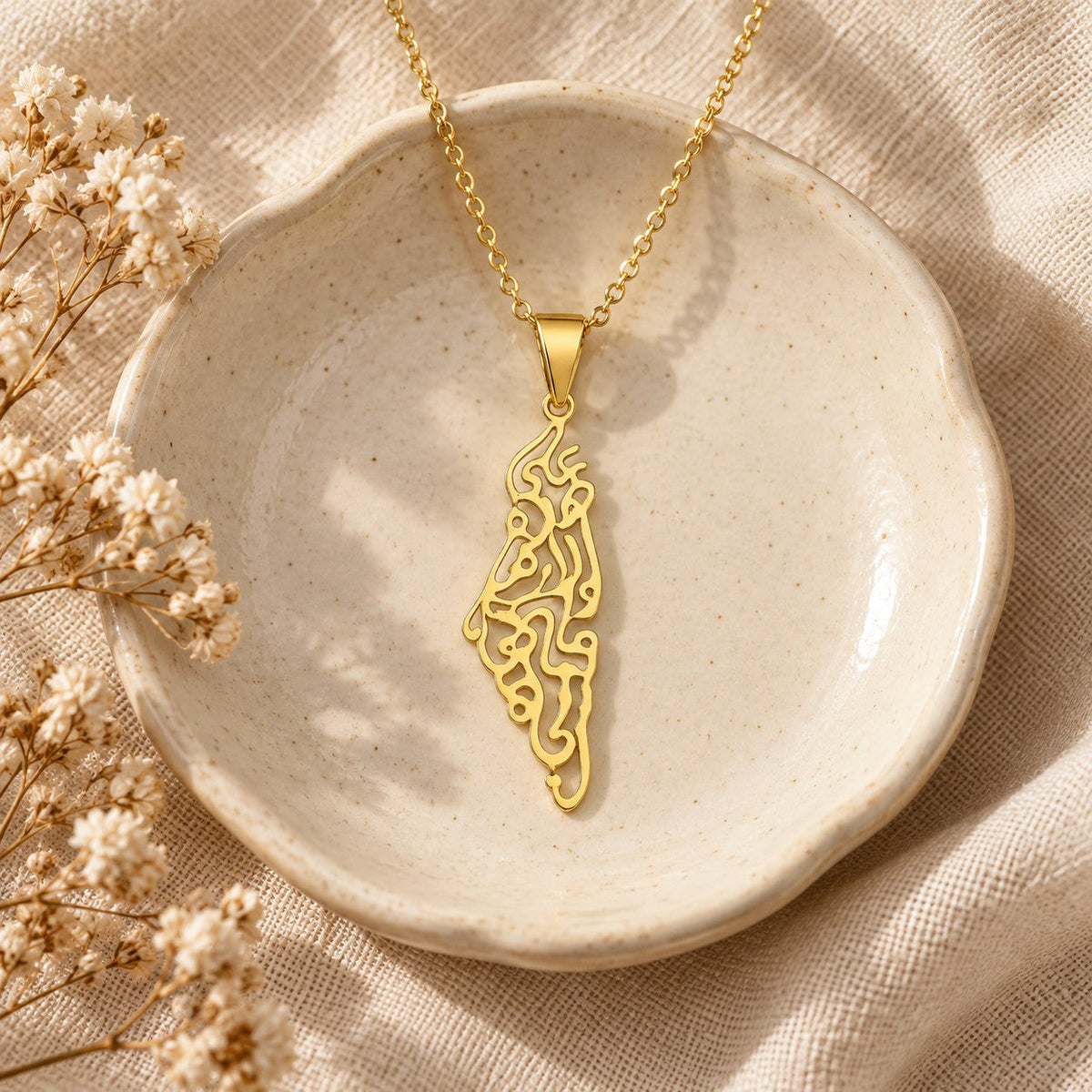 The Palestine Calligraphy Map Necklace in a ceramic trinket dish